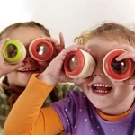 Deux enfants souriants portant des lunettes d'observation colorées, explorant le monde avec curiosité et enthousiasme, dans un contexte éducatif et ludique.
