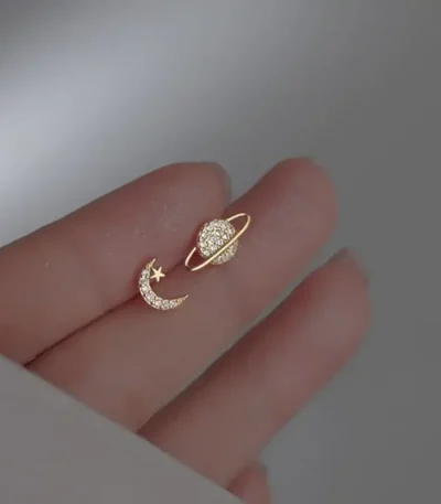 Bijou d'oreille en forme de lune et d'étoile ornée de diamants, symbolisant la celestialité et l'élégance.