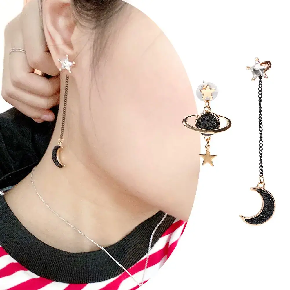 boucle-doreilles-asymetrique-planete-et-lune-noire-et-or-1 Boucles d'oreilles pendantes avec étoiles, lune et planète.