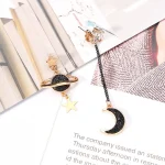 Boucles d'oreilles pendantes avec motifs planètes et lune en métal doré et noir.