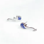 Boucles d'oreilles en forme de sirène en argent avec détails en bleu marine, parfaites pour les amateurs de bijoux inspirés de la mer et de la science.