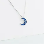 Pendentif en forme de lune bleue avec étoiles, suspendu à une chaîne fine.