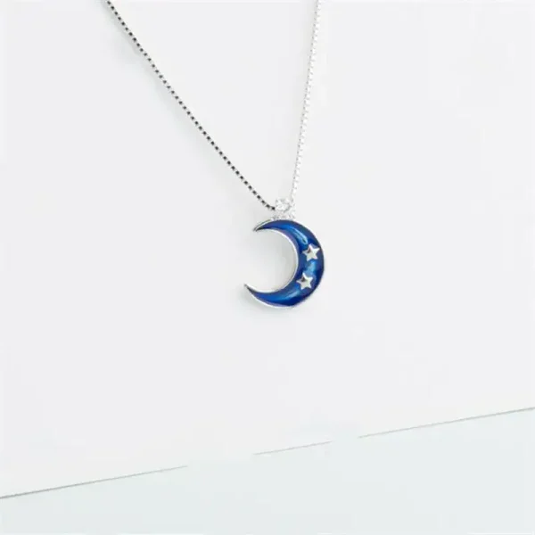 Pendentif en forme de lune bleue avec étoiles, suspendu à une chaîne fine.