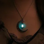 Pendentif lune en métal avec lanterne suspendue, illuminée d'une lumière bleue, porté autour du cou.