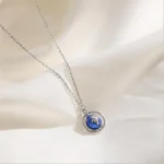 Collier délicat avec pendentif planète Terre en verre bleu et argent.