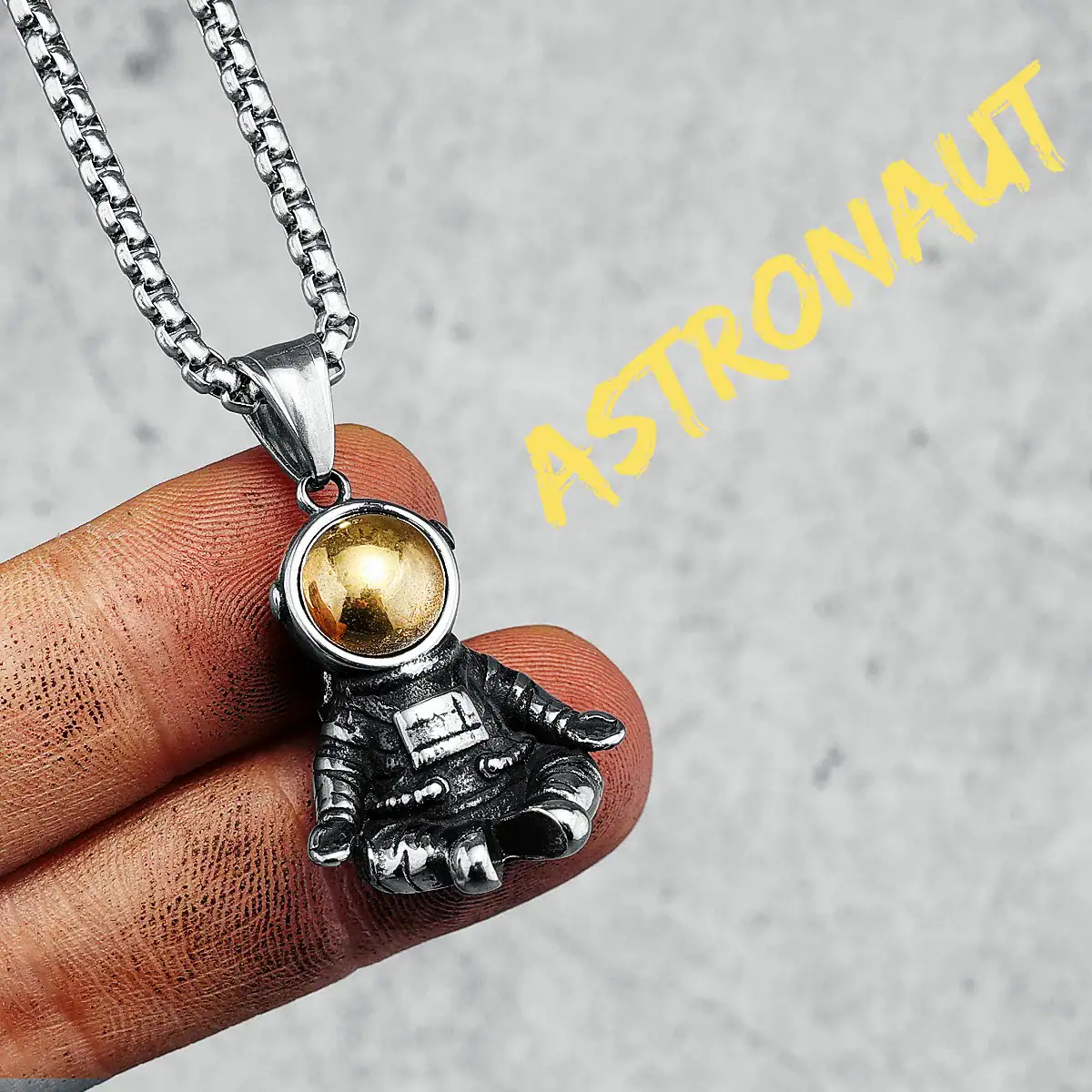 pendentif-astronaute-en-meditation-1 Collier avec pendentif d'astronaute en métal argenté et boule dorée, inspiré de l'espace et de l'exploration spatiale.
