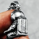 Pendentif en forme d'astronaute en métal argenté, détaillé avec un casque et un sac à dos, parfait pour les amateurs d'espace et de science.