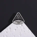 Pièce de décoration en forme de logo Apollo 1969, inspirée de la mission spatiale, posée sur une surface blanche avec un fond noir.