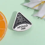Pendentif en métal représentant la mission Apollo 11 de 1969 avec la silhouette de la lune.