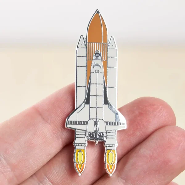 Pin's en forme de vaisseau spatial avec détails en métal, illustrant une fusée prête à décoller, parfait pour les amateurs d'astronomie et de science.