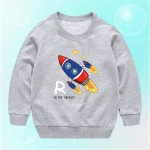Vêtement pour enfant gris avec illustration de fusée colorée et étoiles, parfait pour les amateurs de science et d'astronomie.