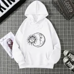 Vêtement à capuche blanc avec design solaire et lunaire.