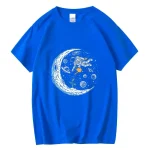 T-shirt bleu avec un motif d'astronaute flottant dans l'espace, entouré de planètes, étoiles et une lune stylisée. Parfait pour les amateurs de science et d'astronomie.
