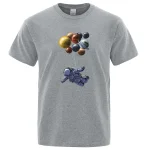 T-shirt gris avec illustration d'un astronaute flottant dans l'espace sous un groupe de planètes colorées. Parfait pour les amateurs de science et d'astronomie.