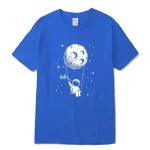 T-shirt bleu avec illustration d'un astronaute suspendu à la lune, entouré d'étoiles, avec le mot "Hello" écrit à côté. Design ludique et scientifique pour les amateurs d'espace.