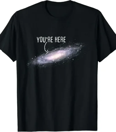 T-shirt galaxie avec texte "You're Here" en blanc sur fond noir, représentant une galaxie spirale avec un message humoristique et cosmique.