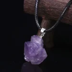 Pendentif en améthyste brute suspendu à un cordon noir, mettant en valeur la pierre semi-précieuse violette.
