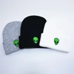 Trois casquettes en tissu gris, noir et blanc avec un logo extraterrestre vert, parfaites pour un style décontracté ou geek.