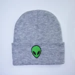 Bonnet gris en laine avec patch d'alien vert brodé, idéal pour un style décontracté et original. Parfait pour les amateurs de science-fiction et de design unique.