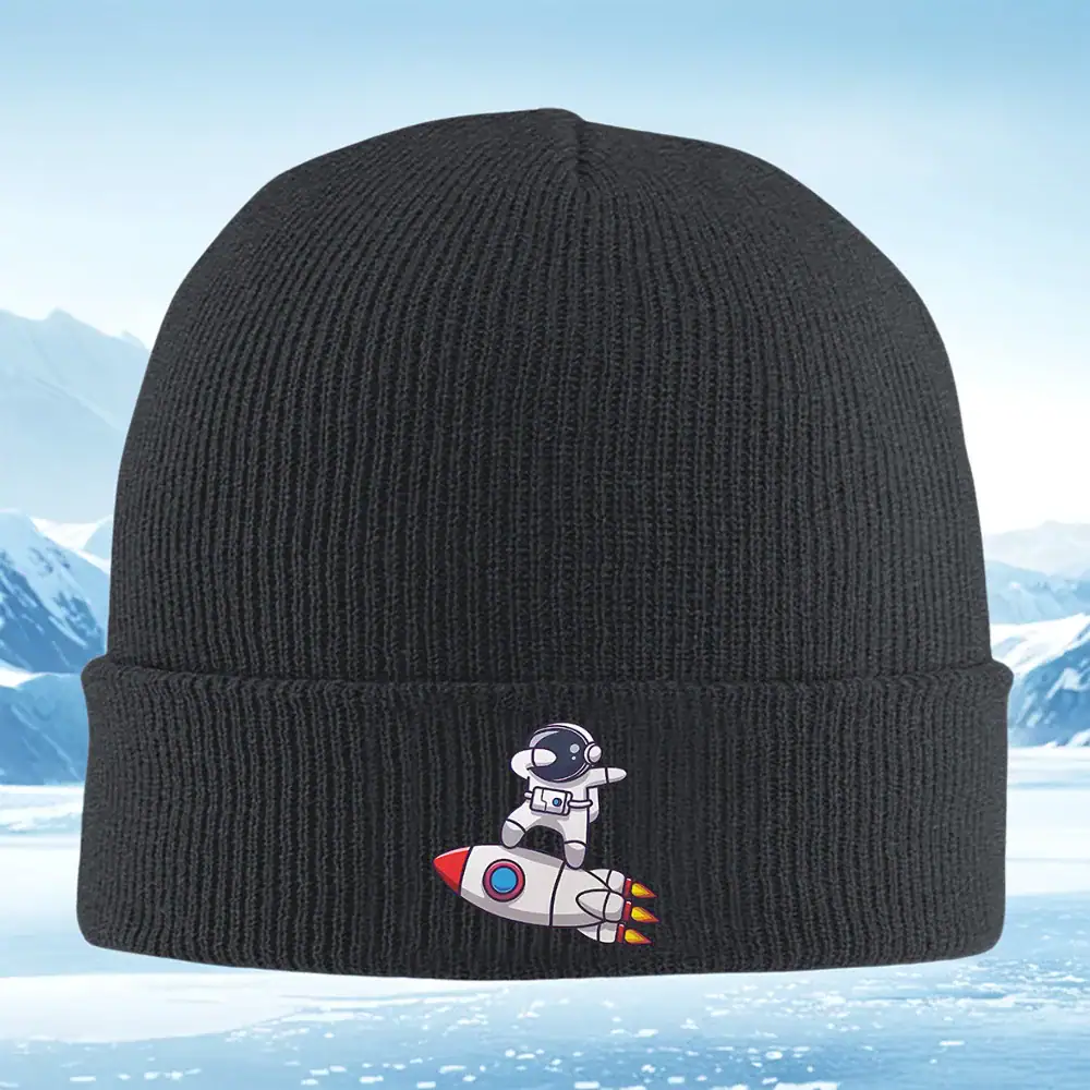 bonnet-astronaute-1 Casquette noire avec broderie d’un extraterrestre en combinaison spatiale sur une fusée. Accessoire de mode original inspiré de l’espace et de la science-fiction.