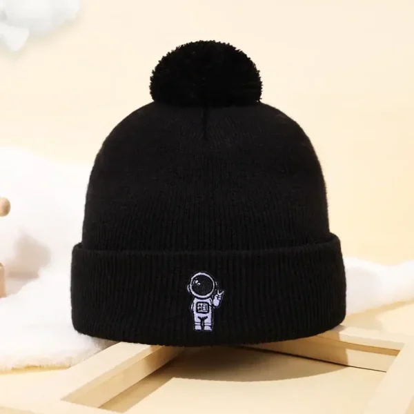 Bonnet noir en laine avec pompon et logo d'un astronaute, idéal pour les amateurs de science et d'astronomie, parfait pour l'hiver ou comme accessoire de décoration scientifique.