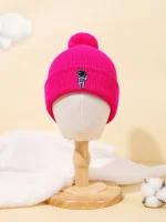 Bonnet rose en laine avec badge d'astronaute, accessoire chaud et tendance pour l'hiver, présenté sur un mannequin en bois dans un décor doux et minimaliste.