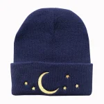 Bonnet en laine bleu marine orné d’un motif lune et étoiles dorées, parfait pour l’hiver ou comme accessoire de mode original.