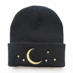 Bonnet en laine noir avec broderie de lune et étoiles dorées, parfait pour un style cosy et mystérieux.