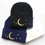 Bonnet en laine avec motif lune et étoiles dorées, disponible en noir, bleu marine et blanc. Parfait pour un style cosy et tendance, idéal pour l'hiver ou comme accessoire original.