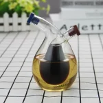 Vase de laboratoire en verre contenant un liquide noir, avec deux tubes en verre inclinés, utilisé pour des expériences scientifiques ou décoratives.