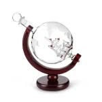 Boussole en verre représentant un globe terrestre avec un bateau miniature à l'intérieur, posée sur un support en bois. Idéal pour la décoration scientifique ou comme objet de collection.