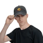Jeune homme portant une casquette noire avec un logo de planète, regardant vers la droite, fond blanc.