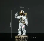 Figurine d'astronaute miniature avec casque doré, mesurant 23,5 cm de haut, 13 cm de large et 11 cm de profondeur, idéale pour la décoration scientifique ou de collection.
