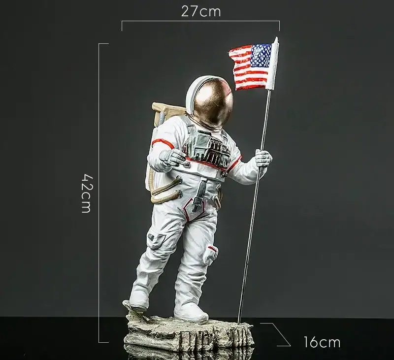 figurine-astronaute-geante-conquete-spatiale-1 Vêtement d'astronaute en figurine avec drapeau américain, hauteur 42 cm, dimensions 27x16 cm, représentant un explorateur spatial en tenue complète, debout sur une base rocheuse.
