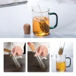 Tasse de thé en verre avec infuseur, contenant du thé infusé, sur fond blanc.