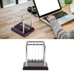 Pendulette Newton en métal avec base en bois foncé, utilisée pour démonstrations scientifiques ou comme décoration de bureau.