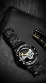 Montre mécanique noire avec mouvement visible, bracelet en acier et détails dorés, alliant élégance et précision pour les amateurs de science et de design.