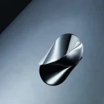 Sculpture contemporaine en métal avec formes fluides et surfaces réfléchissantes, exposée dans un espace minimaliste.
