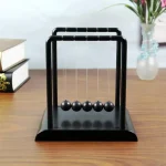 Boule de Newton en bois noir, objet de décoration scientifique, idéal pour les amateurs de physique et de design moderne, à poser sur un bureau ou une étagère.