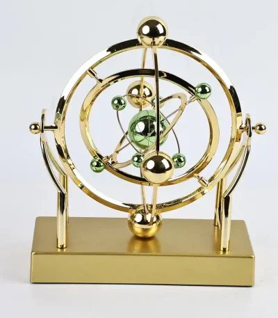 Modèle atomique décoratif en métal doré avec sphères vertes et or, représentant un atome stylisé.