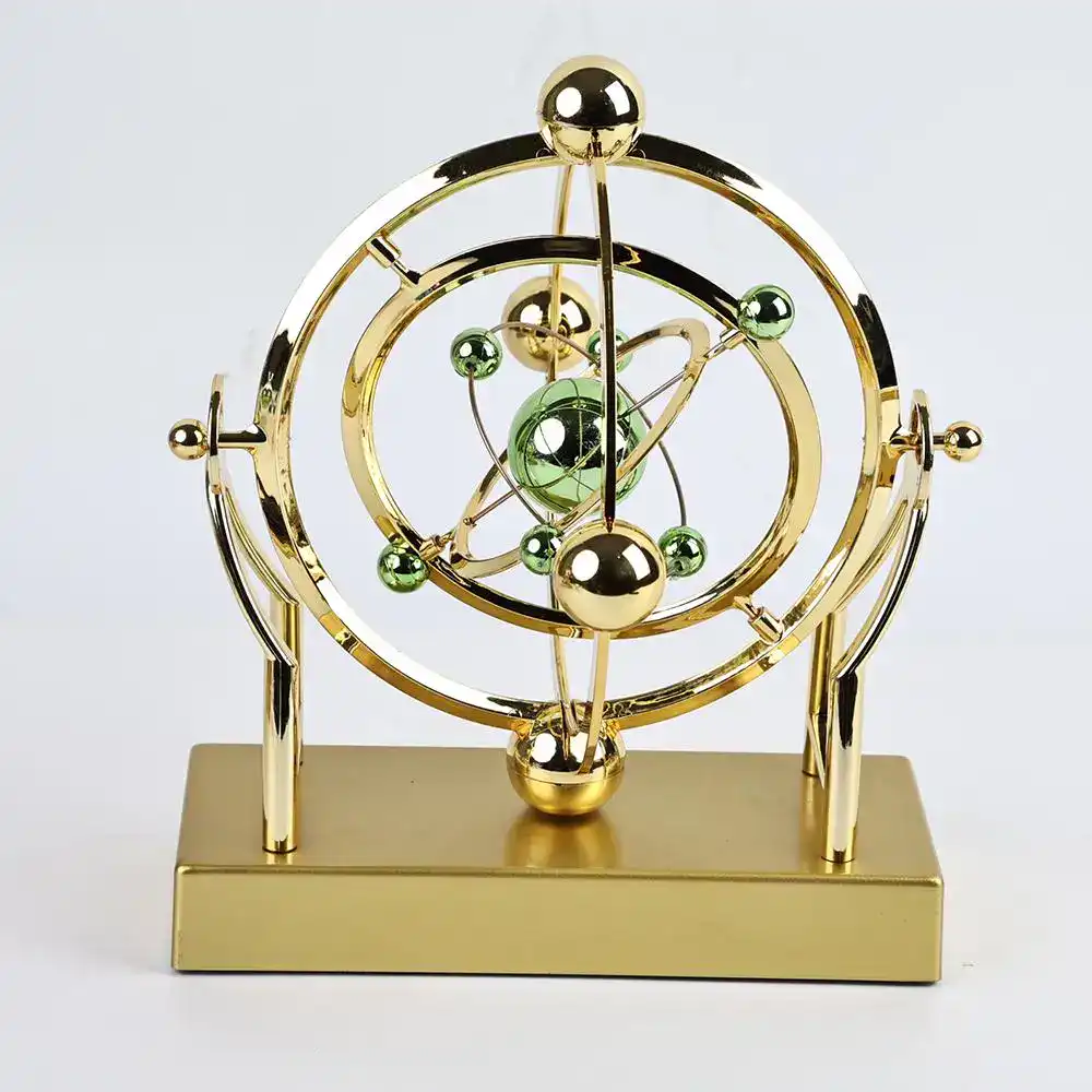 pendule-de-newton-orbital-1 Modèle atomique décoratif en métal doré avec sphères vertes et or, représentant un atome stylisé.