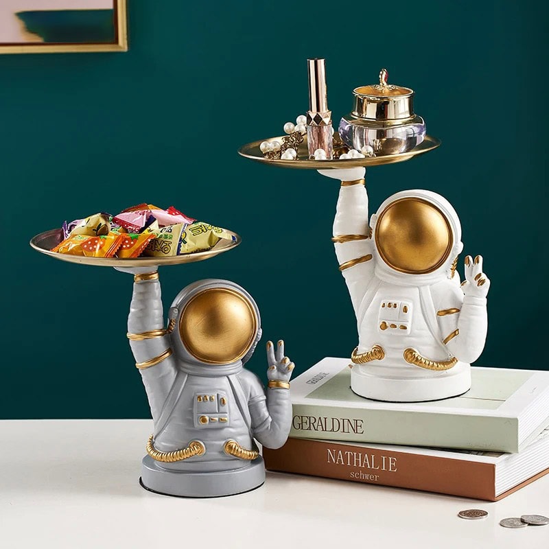 plateaux-astronautes-peace-1 Figurine d'astronaute en céramique blanche et dorée, utilisée comme décoration, tenant un plateau avec des objets de décoration et des bonbons, style moderne et original.
