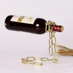 Bouteille de vin suspendue avec chaîne en or et corde en jute, décoration originale pour un intérieur scientifique ou industriel.