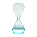 Sablier en verre transparent avec liquide bleu et grains blancs, symbole du temps qui passe, idéal pour la décoration scientifique ou éducative.