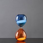Pendentif en forme de sablier avec sable bleu et orange, symbolisant le temps et la science, parfait pour la décoration ou comme accessoire scientifique original.