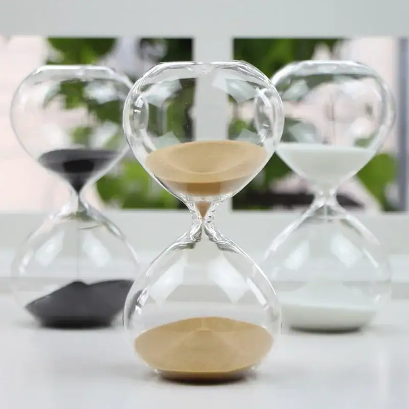 sablier-moderne-5-minutes-1 Sablier en verre avec sable blanc et noir, symbole du temps qui passe, décoratif et scientifique, idéal pour une décoration de bureau ou d'étagère.