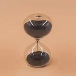 Horloge de sable en verre avec sable noir et transparent, design élégant et moderne, parfait pour la décoration scientifique ou comme objet de collection.