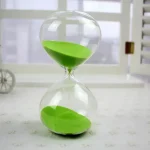 Horloge de sable en verre avec sable vert, symbole de la mesure du temps, idéale pour la décoration scientifique ou éducative.