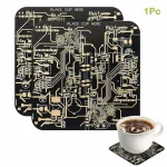 Puce de circuit imprimé noire avec circuits dorés, utilisée comme décoration ou objet scientifique, accompagnée d'une tasse de café sur un sous-verre en circuit imprimé.