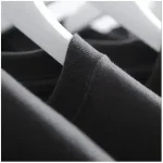 Pull noir en coton sur cintre, vue en gros plan.